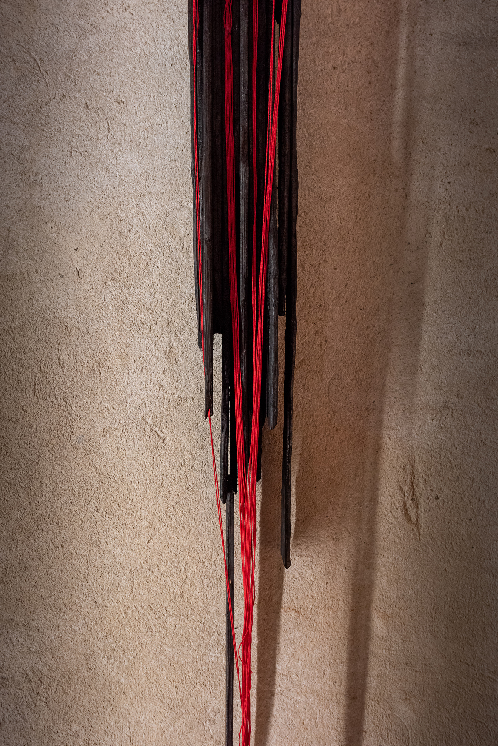 scultura di legno carbonizzato e fili di cotone rosso